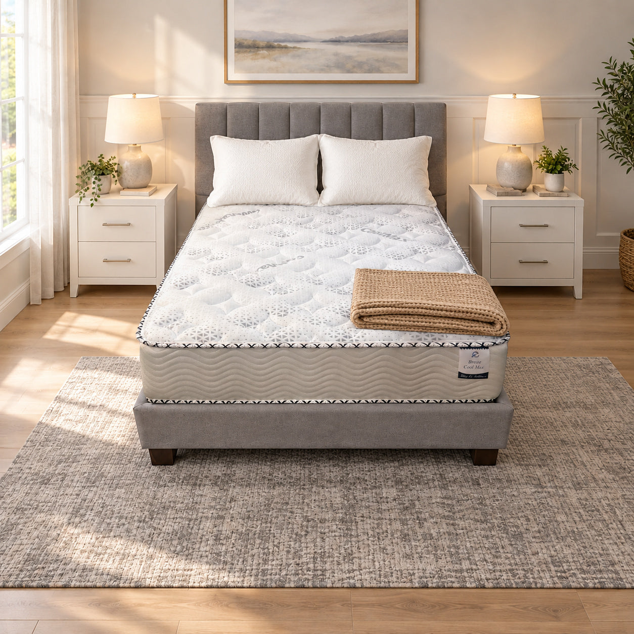 Three Quarter Breeze Cool Max 10" Medium Firm Tight top mattress on a gray upholstered bed with two white pillows and a tan knit throw, in a bedroom with white nightstands, table lamps and a framed landscape print